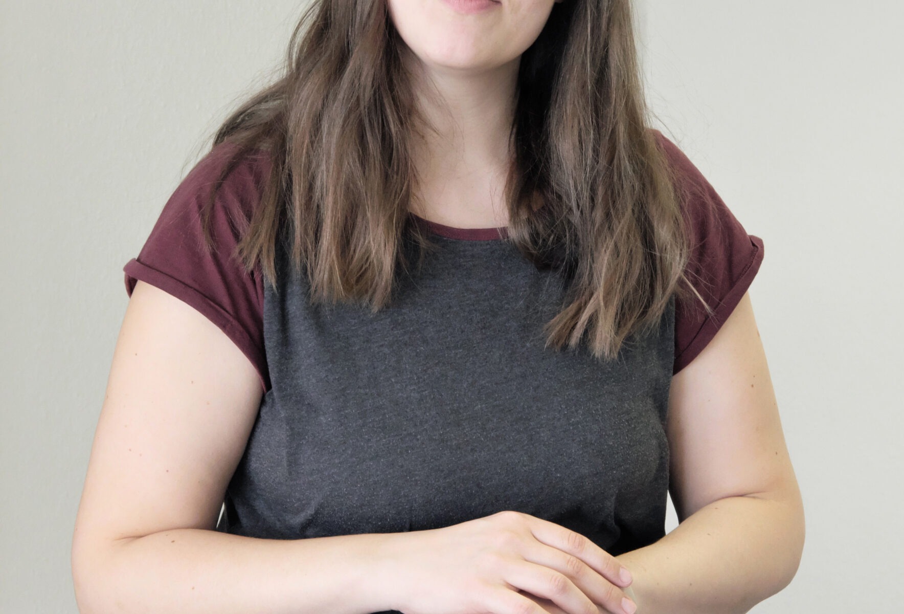 Frau in grauem T-Shirt steht.