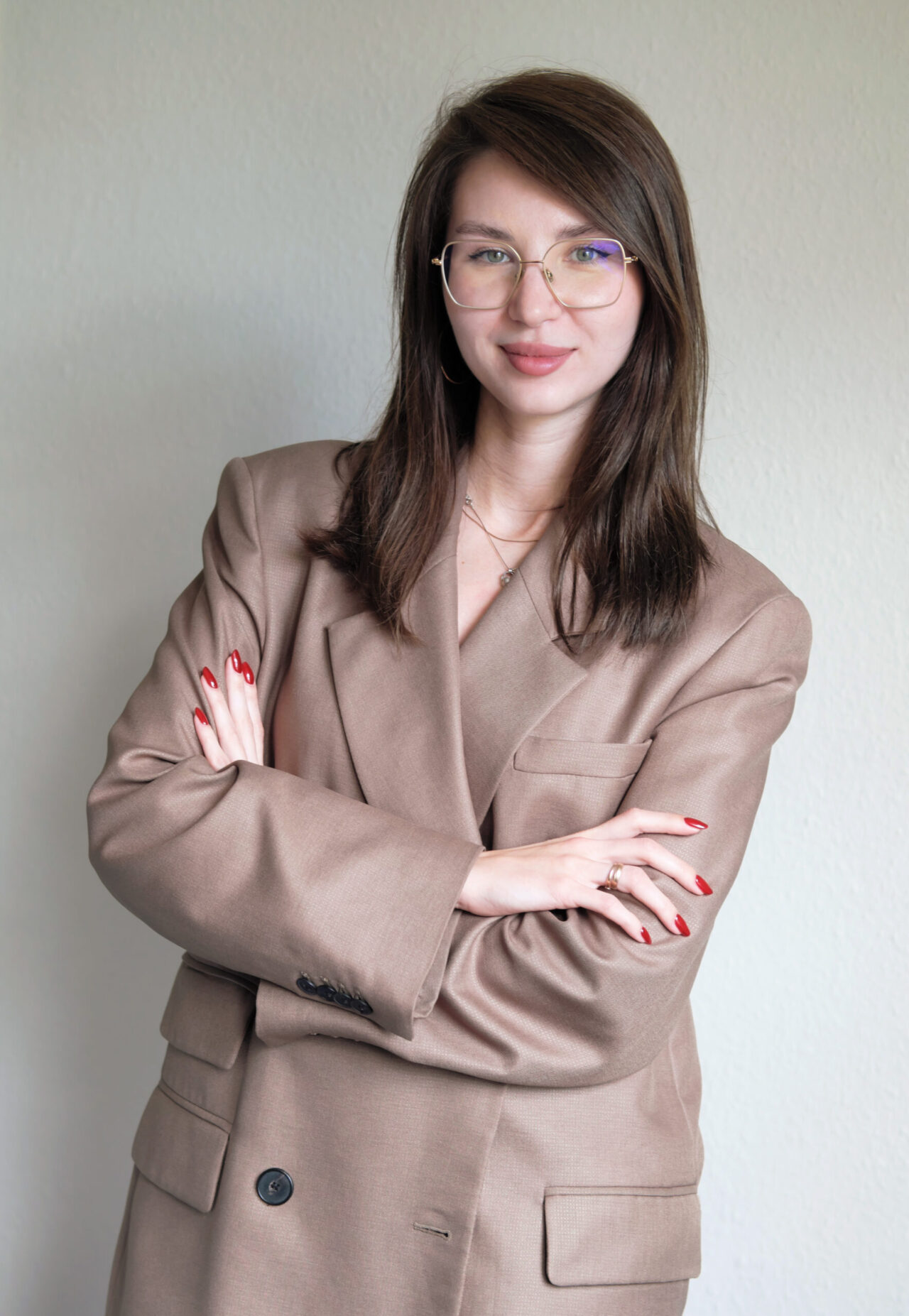 Frau in beigem Blazer mit verschränkten Armen.