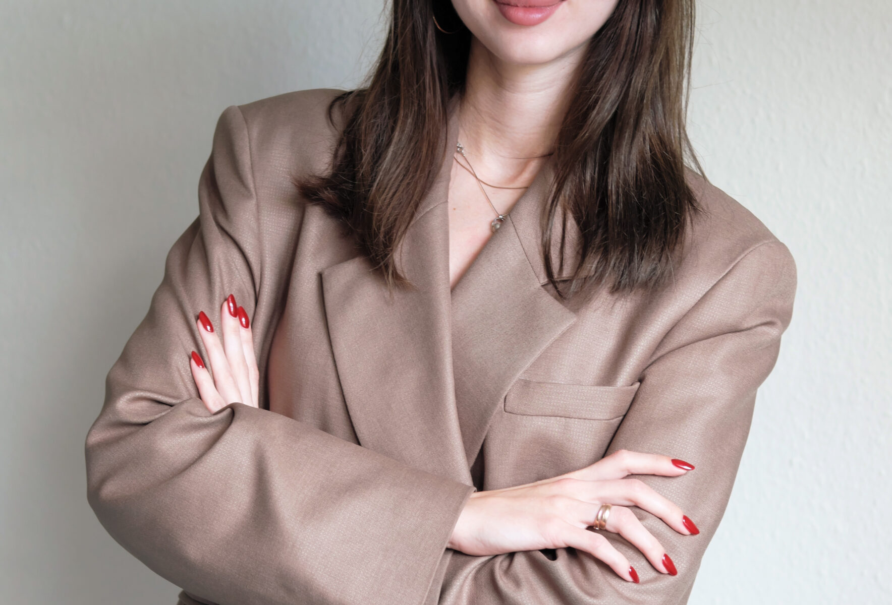 Frau in beigem Blazer mit verschränkten Armen.